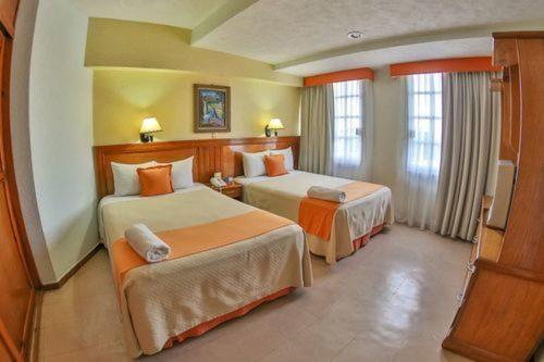 a hotel room with two beds and a television at Hotel Báez Carrizal in Villahermosa