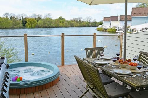 a wooden deck with a table and a hot tub at Lapwing Lake Lodge in Cirencester
