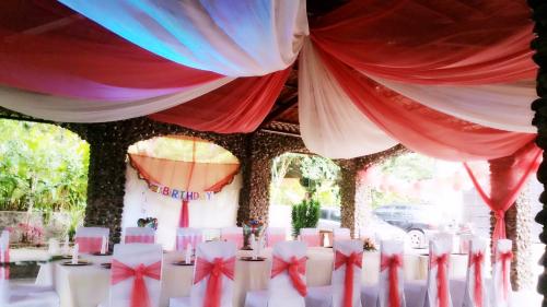 a table with white chairs and red and white curtains at Apart Hotel Acuarious de Luis in Estelí