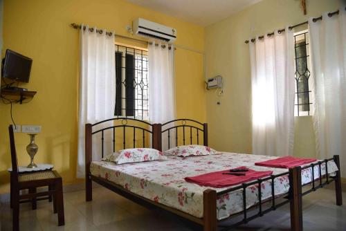 a bedroom with a bed and a tv and windows at Niki Guest House in Candolim