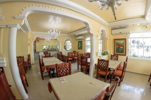 um restaurante com mesas e cadeiras num quarto em Hotel Báez Carrizal em Villahermosa