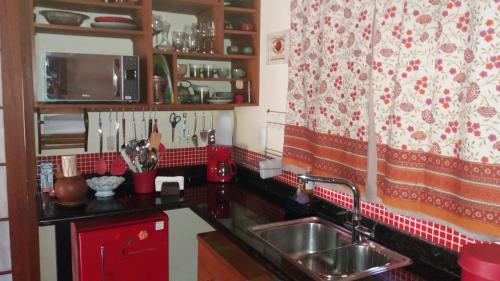 a kitchen with a sink and a red and white curtain at Be Hospedagem in Lumiar
