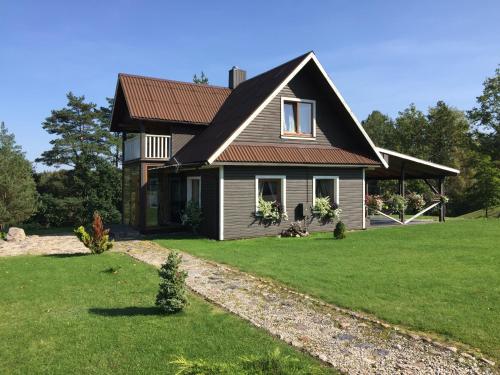 a house with a brown roof on a green yard at Kaimo turizmo sodyba Geras in Leliūnai