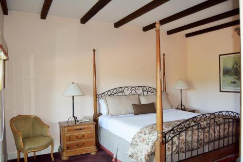 a bedroom with a four poster bed and a chair at Vineyard Country Inn in St. Helena