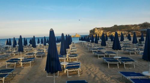 a bunch of chairs and umbrellas on a beach at Villa Lucia With Salt Pool in Fontane Bianche