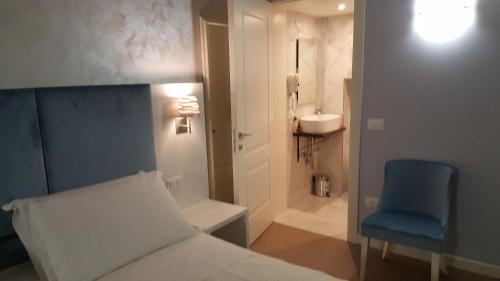 ヴェネツィアにあるMaison d'Elite Guest Houseのベッドルーム1室(ベッド1台、青い椅子、バスルーム付)