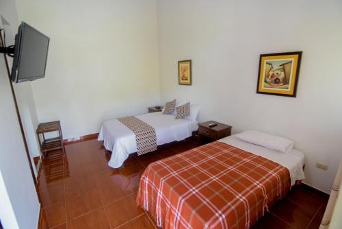 a room with two beds and a flat screen tv at La Choza Bungalows in Tambo Grande