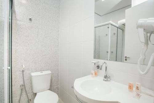 een badkamer met een toilet, een wastafel en een spiegel bij Travel Inn Bras in Sao Paulo