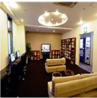 a living room with two couches and a tv at Capsule Hotel Kobe Sannomiya (Male Only) in Kobe