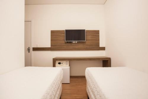 two beds in a room with a tv on the wall at Travel Inn Express Hotels Brás in Sao Paulo