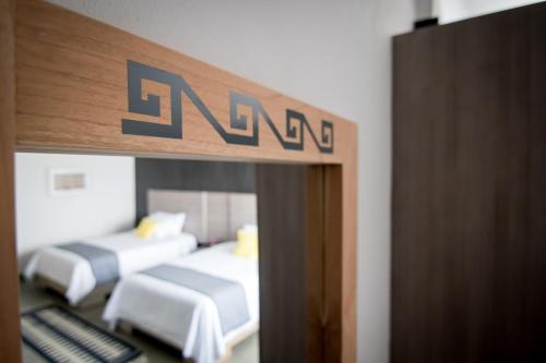 two beds in a room with a sign on the wall at Maria Ines Hotel Suite in Oaxaca City