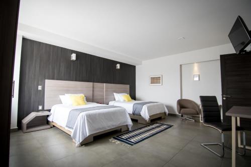 een hotelkamer met 2 bedden en een televisie bij Maria Ines Hotel Suite in Oaxaca City