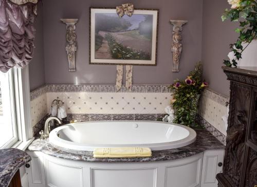 a bath tub in a bathroom with a picture on the wall at The Richard Johnston Inn & 1890 Caroline House in Fredericksburg