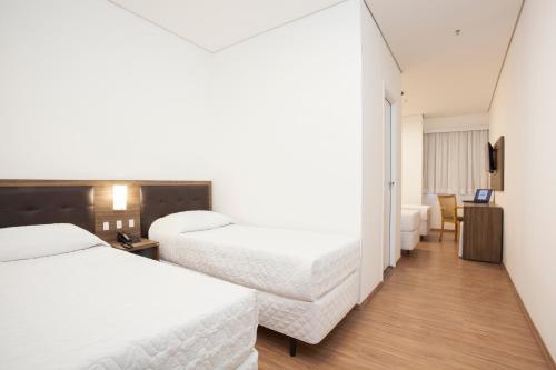 a hotel room with two beds and a desk at Travel Inn Express Hotels Brás in Sao Paulo
