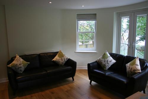 a living room with two leather couches and two windows at Highlands Apartment 2 in Shanklin