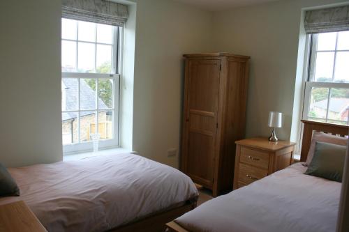 1 dormitorio con 2 camas, vestidor y 2 ventanas en Highlands Apartment 2, en Shanklin