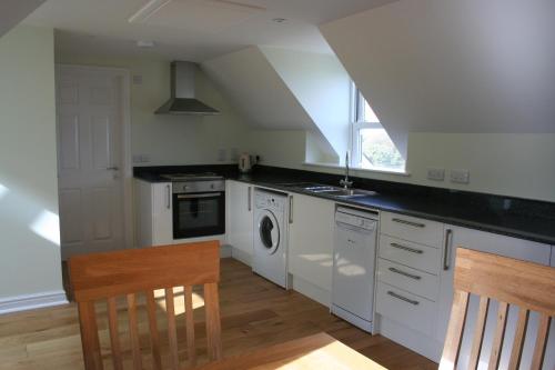 a kitchen with white cabinets and a sink and a stove at Highlands Apartment 4 in Shanklin