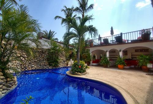 a swimming pool in front of a house with palm trees at Villas Carrizalillo in Puerto Escondido