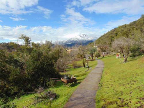 a path with a bench and a snow covered mountain at Cabañas Puente Negro in Puente Negro