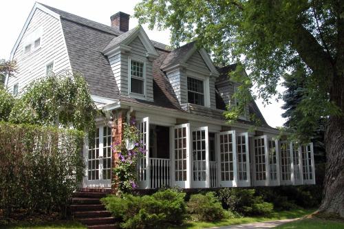 uma casa branca com um alpendre com janelas brancas em Mill House Inn em East Hampton