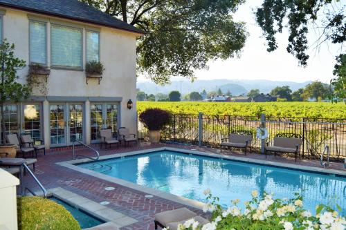 a swimming pool in front of a house with a vineyard at Vineyard Country Inn in St. Helena