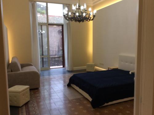 a bedroom with a bed and a couch and a chandelier at Suite con terrazza in centro storico in Catania