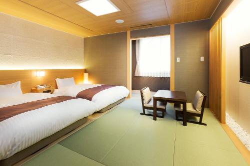 a bedroom with two beds and a desk and a television at Niseko Hot Spring Ikoino Yuyado Iroha in Niseko