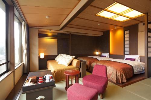 a hotel room with two beds and a chair at Kasuien Minami in Matsue