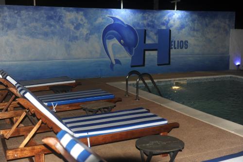 a pool with lounge chairs and a dolphin mural at Residence Helios in Abidjan