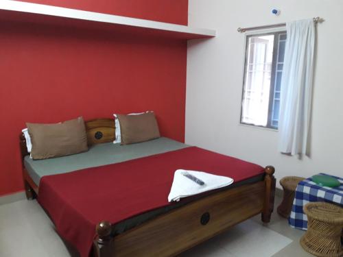 a bedroom with a bed with a red wall at Squirrel Nest Guest House in Mahabalipuram