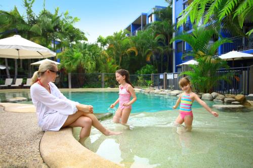two women and a man are relaxing in a pool at Portobello By The Sea in Caloundra