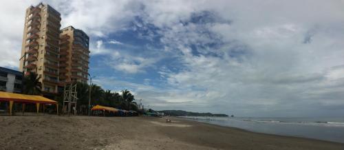 a beach with a tall building and the ocean at Apartamento en Atacames con vista al mar in Atacames