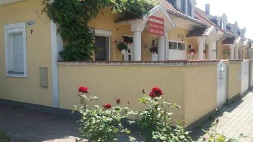 a building with red roses in front of a fence at David Apartman in Gyula