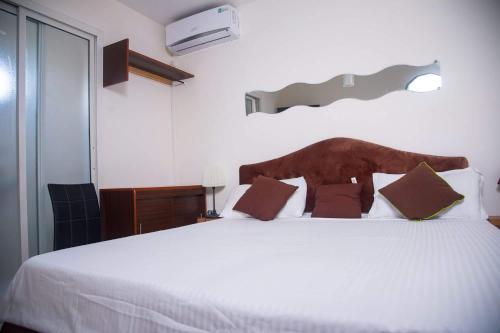 1 dormitorio con 1 cama blanca grande con almohadas marrones en Residence Maeva, en Mamoudzou