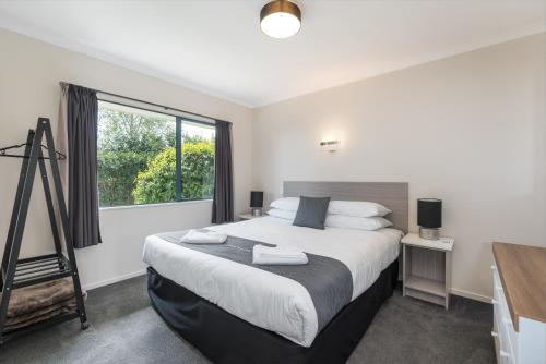 a bedroom with a large bed and a window at Matakana Motel in Matakana