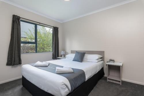 a bedroom with a large bed and a window at Matakana Motel in Matakana