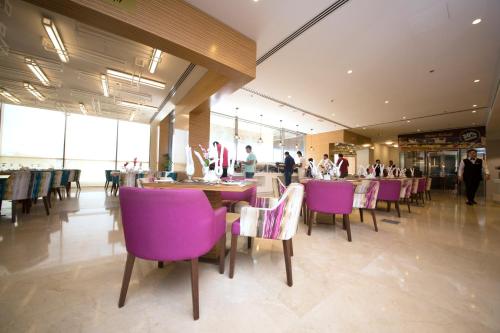 a restaurant with purple chairs and tables and people at Best Western Plus Pearl Creek in Dubai