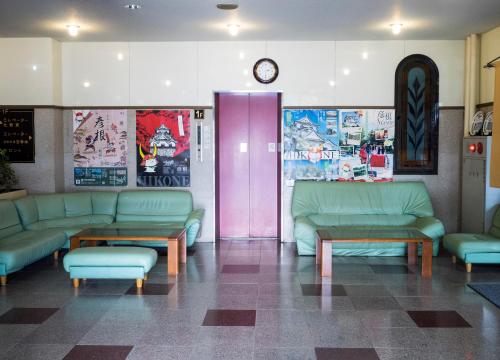 a waiting room with green couches and a pink door at Hikone Station Hotel in Hikone