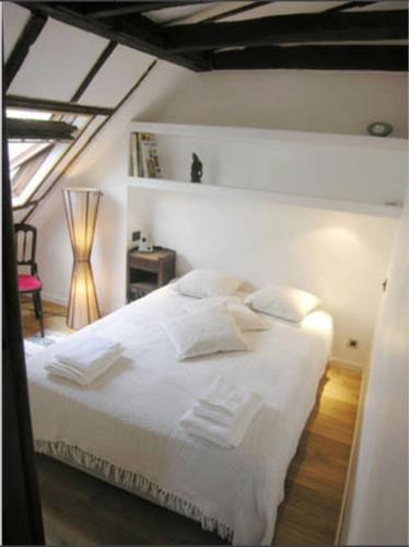 une chambre avec un lit avec des draps blancs et des oreillers dans l'établissement SOHO CENTER/MARAIS/POMPIDOU/LOUVRE, à Paris