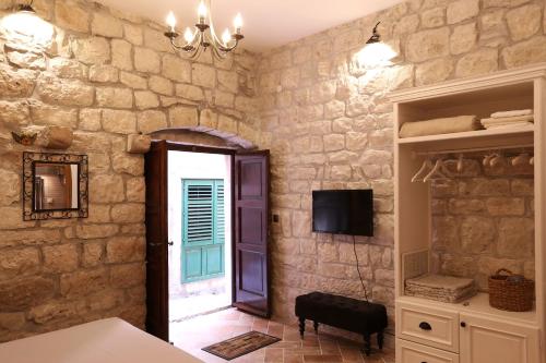 a stone walled room with a door and a television at Luxury apartment Gabriela in Korčula