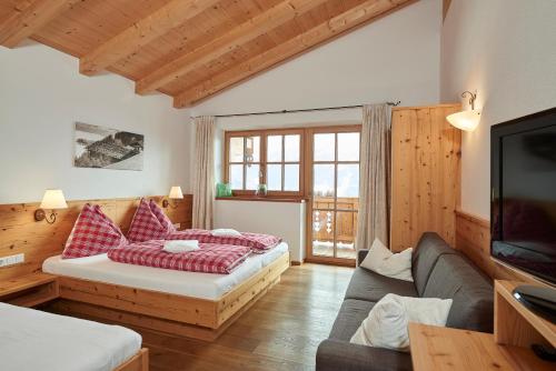 a living room with two beds and a television at Jausenstation Pfefferbauer in Zell am See