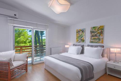 a bedroom with a large white bed and a chair at The White Villa at Sani in Sani Beach