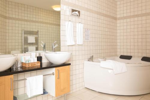 a bathroom with a tub and two sinks and a bath tub at Color Hotel Skagen in Skagen