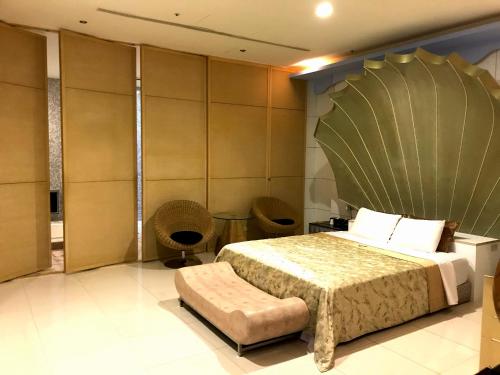 a bedroom with a large bed and two chairs at Fortune Villa Motel in Tamsui