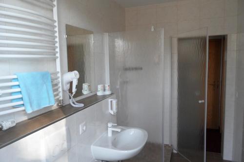 a white bathroom with a sink and a shower at Landguthotel Hotel-Pension Sperlingshof in Dallgow