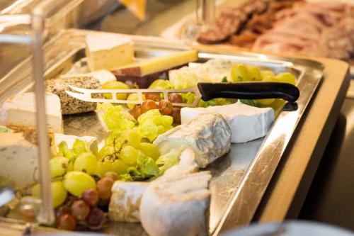a tray filled with different types of cheese and grapes at Hotel Die Kleine Blume in Erfweiler