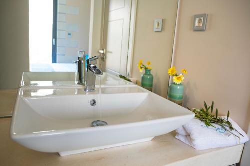 lavabo blanco en el baño con espejo en Titans Villas, en Kókkinon Khoríon