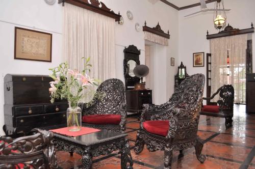 a living room with two chairs and a table at WelcomHeritage Panjim Inn in Panaji