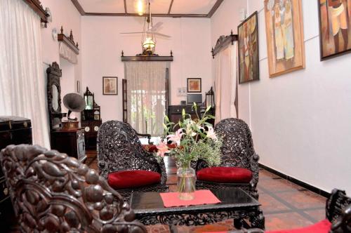 a living room with two chairs and a table with flowers at WelcomHeritage Panjim Inn in Panaji