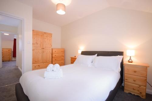 una camera da letto con un grande letto bianco con due asciugamani di Town or Country - Jessie Terrace House B a Southampton